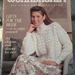 May include: The Workbasket magazine cover from May 1989 features a woman wearing a white crocheted sweater and a floral skirt. The magazine title is "The Workbasket and Home Arts Magazine" and the cover text reads "Gifts for the Bride - or to enjoy yourself".