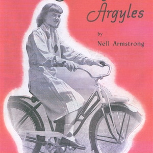 May include: A vintage knitting pattern booklet cover featuring a woman riding a bicycle. The cover is pink with white text that reads "Two Needle Argyles by Nell Armstrong" and "Easy to make". The booklet is volume 26 and costs 20 cents.