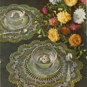 Puede incluir: Naturaleza muerta con dos cuencos y platos de cristal transparente, cada uno con líquido y flores blancas, sobre tapetes de ganchillo amarillo-verdoso. Una cuchara de plata y un ramo de flores coloridas completan la escena, de estilo vintage.