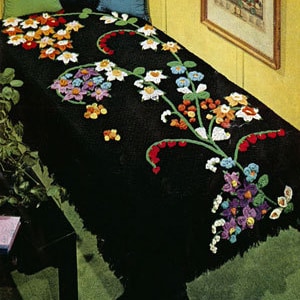 Peut inclure: Une couverture en crochet noire avec un motif floral dans les tons de rouge, orange, jaune, vert, violet et blanc.