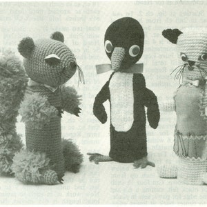 Puede incluir: Tres animales de peluche tejidos a crochet: una ardilla con una cola tupida, un pingüino con el vientre blanco y un gato con una pajarita blanca.