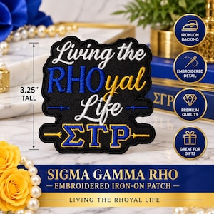 May include: A black embroidered iron-on patch measuring 3.25 inches tall. The patch features the white text Living the, blue and gold text RHOyal, white text Life, and blue and gold Greek letters ΣΓΡ. The design includes horizontal lines with arrow accents.
