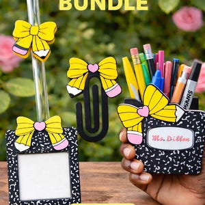 May include: A school-themed bundle set featuring a pen holder, photo frame, paperclip, and straw. Each item is adorned with yellow bow accents and a black and white composition notebook design. The pen holder is filled with various pens and pencils.