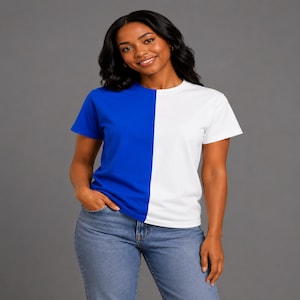 May include: A short-sleeved t-shirt featuring a split-color design with a solid royal blue left side and a solid white right side, paired with blue denim jeans. The garment has a classic crew neckline and a straight hemline, providing a clean look.