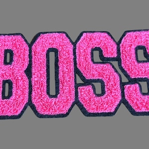 May include: Pink felt "BOSS" letters with black outlines. The letters are in a bold, blocky font.
