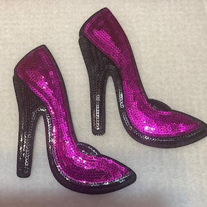 Peut inclure: Deux chaussures à talons hauts en sequins roses avec des talons noirs. Les chaussures sont en tissu et ont une finition scintillante.