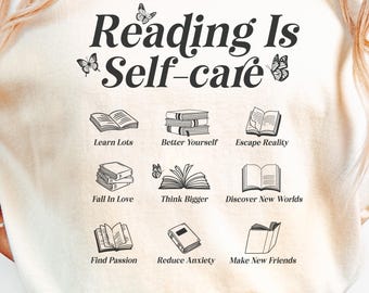 May include: Cream-colored t-shirt with the text "Reading Is Self-care" and illustrations of books. The shirt also features the phrases "Learn Lots," "Better Yourself," "Escape Reality," "Fall in Love," "Think Bigger," "Discover New Worlds," "Find Passion," "Reduce Anxiety," and "Make New Friends."