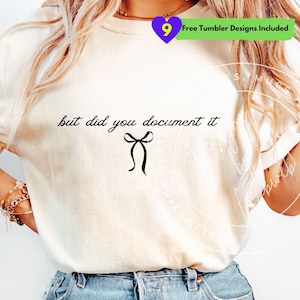May include: Cream-colored t-shirt with the phrase "but did you document it" in black script, accompanied by a black bow graphic. A purple heart-shaped graphic with the number 9 and text "Free Tumbler Designs Included" is in the upper right corner.