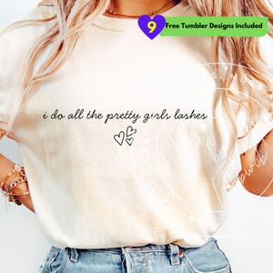 May include: Cream-colored t-shirt with the text "i do all the pretty girls lashes" in black script, accompanied by three small heart illustrations. A purple heart with the number 9 and text "Free Tumbler Designs Included" is in the upper right corner.