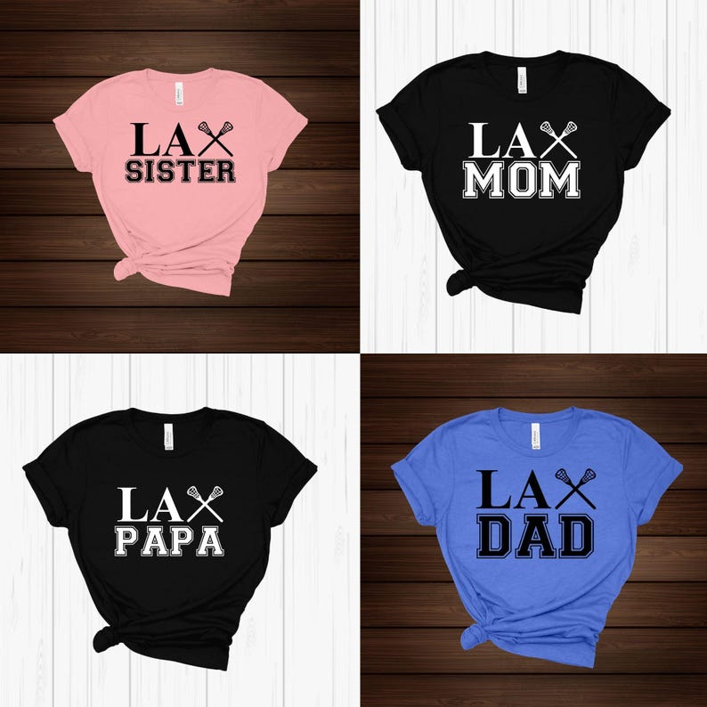 Op de afbeelding: Vier T-shirts met verschillende lacrosse-thema ontwerpen. De shirts zijn roze, zwart, zwart en blauw. De ontwerpen omvatten "LAX Sister", "LAX Mom", "LAX Papa" en "LAX Dad".