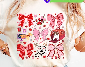 May include: Cream-colored t-shirt featuring a Valentine's Day design with bows, hearts, paw prints, and a cat in a carrier. The design includes the text "Free Tumbler Designs Included" in a green rectangle.
