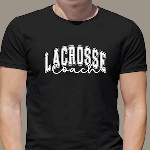 Op de afbeelding: Zwart T-shirt met witte tekst die "Lacrosse Coach" zegt in een lettertype in varsity-stijl.