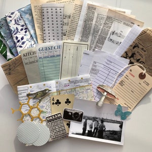 Op de afbeelding: Een verzameling vintage ephemera, waaronder papieren restjes, kaarten, muziekbladen en een kleine bruine papieren zak. De ephemera is gerangschikt op een wit oppervlak en omvat een verscheidenheid aan kleuren en texturen.