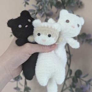 May include: Three small, fuzzy, plush animal figures in black, white, and a mix of white and tan. Each figure features round ears, dark bead eyes, and a small stitched nose. The figures have a soft, textured appearance and are grouped together.