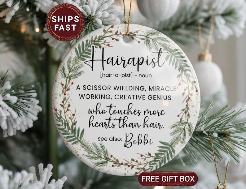 May include: A round ceramic ornament with the word "Hairapist" in black script, surrounded by a green and red floral design. The text defines "Hairapist" and includes the phrase "who touches more hearts than hair."