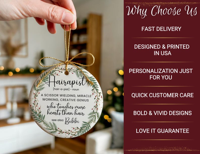 May include: A round, white ceramic ornament with the word "Hairapist" in black script. The ornament has a gold string for hanging and is decorated with green and brown botanical elements. Text on the ornament describes a hair stylist.