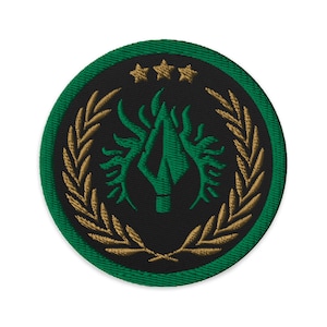 May include: A green and gold embroidered patch with a stylized flame design, three stars, and a laurel wreath.
