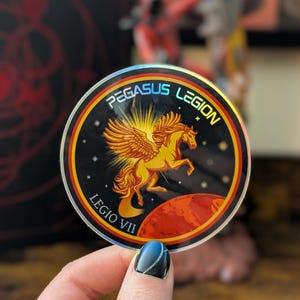 May include: A round sticker with a holographic finish featuring a winged horse, a red planet, and the text "PEGASUS LEGION LEGIO VII".