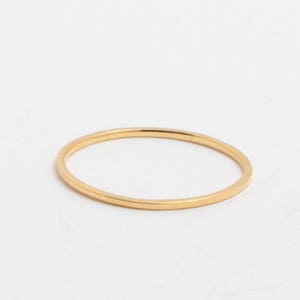 May include: A thin, gold-colored ring. The ring is circular and appears to be made of metal. The ring is set against a white background.