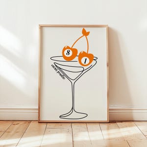 Puede incluir: Un dibujo en blanco y negro de una copa de martini con dos cerezas naranjas. Las cerezas están numeradas 8 y 1, como bolas de billar.