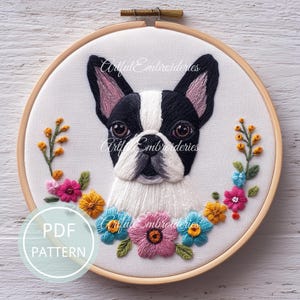 May include: Embroidered hoop art featuring a Boston Terrier dog with black and white fur, pink-lined ears, and a floral wreath. The text "Artful Embroidieries" is visible. The hoop is made of wood, and the text "PDF PATTERN" is also visible.