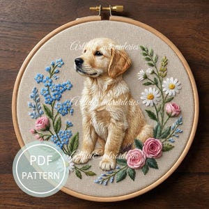 以下が含まれることがあります： ゴールデンレトリバーの子犬の刺繍アート。青い勿忘草、ピンクのバラ、白いデイジーに囲まれています。刺繍は木の枠にセットされています。「PDF PATTERN」の文字が左下の円の中にあります。