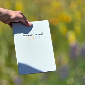 May include: A light blue journal with the text "Explorer's Journal" and five small icons representing the elements: earth, fire, water, air, and wood.