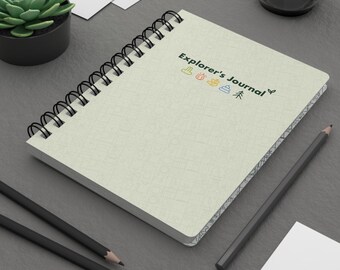 May include: A beige spiral bound journal with the text "Explorer's Journal" and a row of five small icons above the text. The icons are a boot, a fire, a leaf, a pile of poop, and a tree. The journal has a patterned border.