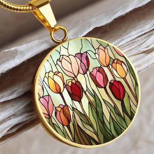 May include: A gold necklace with a round pendant featuring a stained glass design of colorful tulips. The pendant is surrounded by a gold frame.