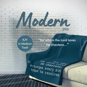 May include: A teal throw blanket with the text "Modern" in white lettering. The blanket is folded on a white couch with a white brick wall in the background. The text "for whom the Lord loves he chastens..." is printed on the blanket in white lettering.