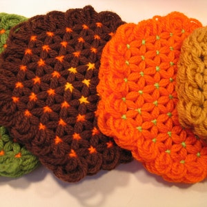 May include: Four crocheted pot holders in different colors and patterns. The pot holders are green, brown, orange, and tan. They are all made with a flower-like design.