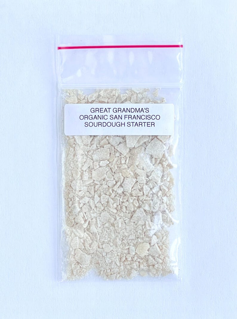 May include: A clear plastic bag with a red zipper closure contains a white sourdough starter. The bag has a white label that reads "Great Grandma's Organic San Francisco Sourdough Starter."