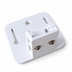 Può includere: Una staffa di montaggio in plastica bianca con una base rettangolare piatta dagli angoli arrotondati, due fessure verticali e un foro circolare centrale. La sezione verticale include un alloggiamento quadrato con due piccoli inserti filettati metallici.