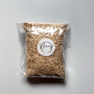 May include: A clear plastic bag filled with light brown wood shavings. A circular white sticker is centered on the front of the bag, featuring the text Alexas Pets in a black script font, surrounded by two small green leaf illustrations.