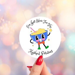 May include: A round sticker featuring a cartoon bowl of mashed potatoes with a face, bow tie, and green shoes. The text "I'm Just Here for the Mashed Potatoes" is written around the bowl.