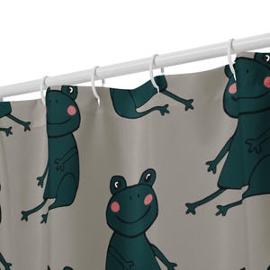以下が含まれることがあります： 薄い灰色の背景に、ピンクの頬を持つティール色の漫画のカエルの繰り返しパターンが特徴のシャワーカーテン。 カエルは曲がった腕と脚を持っており、笑顔です。 白いシャワーカーテンリングが上部に付いています。