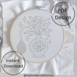 May include: An embroidery hoop with a floral design featuring a vase and flowers. The design is outlined in black on white fabric. Text in the image says "PDF Design" and "Instant Download". A pair of scissors is also in the image.