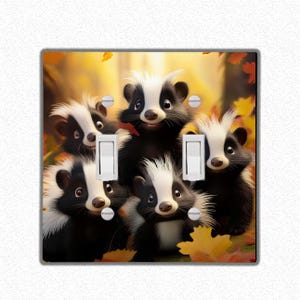 Peut inclure: Une plaque de prise de courant représentant un groupe de cinq mouffettes de dessin animé avec une fourrure noire et blanche, entourées de feuilles d'automne. Les mouffettes sourient et regardent la caméra.