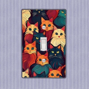 Könnte beinhalten: Ein Lichtschalter-Abdeckung mit einem bunten Muster aus Katzen. Die Katzen sind in verschiedenen Farben, darunter Orange, Schwarz, Weiß und Braun. Die Schalterabdeckung hat eine Standardgröße und ist für die meisten Lichtschalter geeignet.