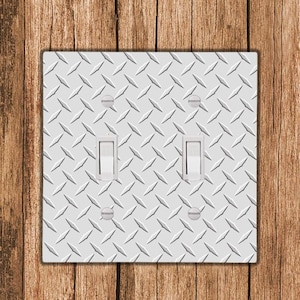 May include: A white light switch cover with a diamond plate pattern. The cover has two toggle switches.