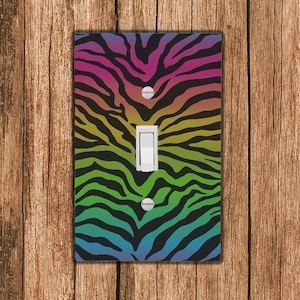 May include: A light switch cover featuring a rainbow zebra print design. The cover is black with rainbow stripes.