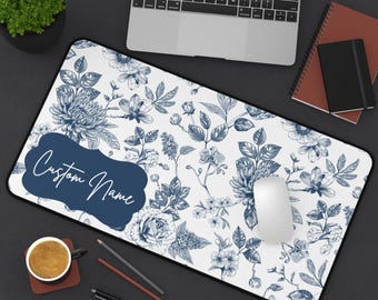May include: A white desk mat with a blue floral pattern. The mat has a blue label with the text "Custom Name".