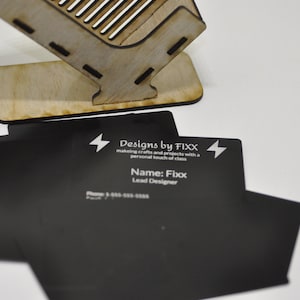 May include: Black business cards with white text. The text reads "Designs by FIXX", "making crafts and projects with a personal touch of class", "Name: Fixx", and "Lead Designer".