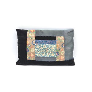 May include: Rectangular decorative pillow with a patchwork design. The pillow features a black velvet base, a gray center section, and a central patchwork square with floral and patterned fabrics in blue, brown, and orange. The pillow is approximately 18 inches long.