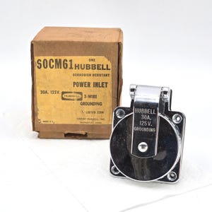 May include: A new Hubbell 30A 125V power inlet with a corrosion-resistant design. The power inlet is chrome-plated and has a hinged cover. The original cardboard box is included, with the text "SOCM61 HUBBELL POWER INLET".