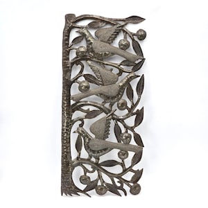 May include: A silver-colored metal wall art piece featuring a tree with three birds perched on branches with leaves and round fruit. The birds have detailed wing patterns. The tree trunk is on the left side of the rectangular art piece.