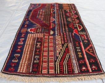 May include: A colorful rug with intricate geometric patterns in shades of red, blue, black, and white. The rug has a fringed edge and is made of wool.