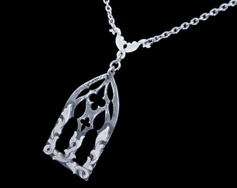 May include: Silver necklace with a detailed, ornate pendant shaped like a gothic arch window.