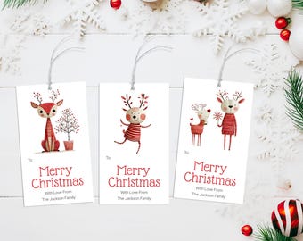 May include: Three white rectangular Christmas gift tags with illustrations of reindeer and the text "Merry Christmas." Each tag has a string for attaching to a gift. Festive holiday decor surrounds the tags, including ornaments and greenery.