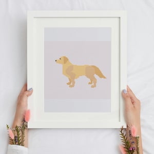 May include: A framed print featuring a pixelated illustration of a golden retriever dog in shades of yellow and tan. The artwork is set against a light gray background and is held by hands with floral accents.